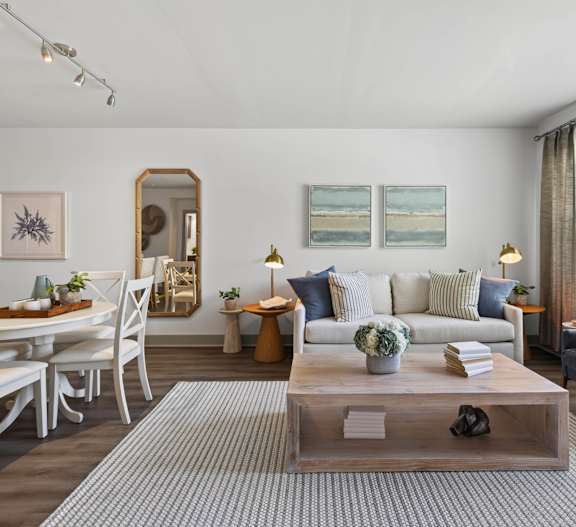 A living room with a white sofa, a coffee table, and a dining table with chairs.