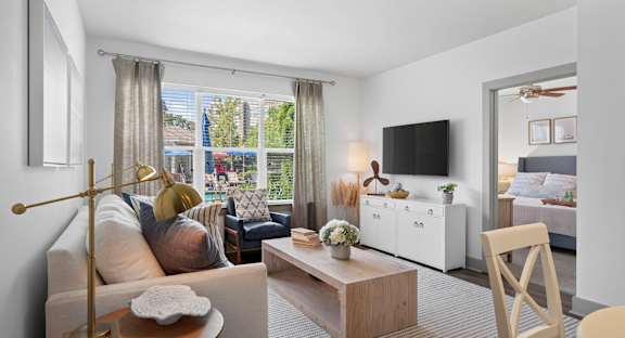 A living room with a white sofa, a coffee table, and a dining table with chairs.