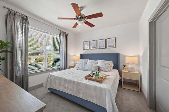A bedroom with a bed, nightstand, and window with curtains.