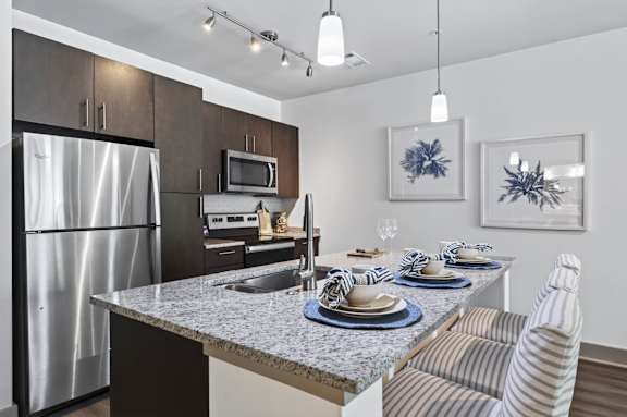A modern kitchen with a dining table set for two.