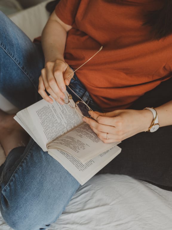 a woman sitting on a bed reading a book