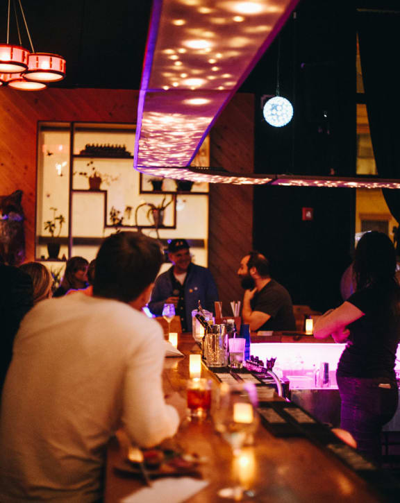a bar with people sitting at it and standing at the bar