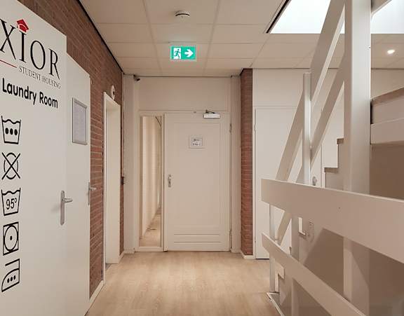 A hallway with a sign that says "XIOR Student Housing Laundry Room".