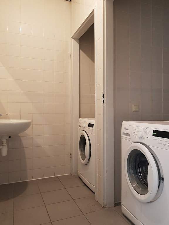 A white washing machine sits in a laundry room.
