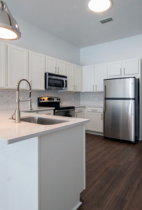 Kitchen at Rise Lakeview with wood-style floors, stainless steel appliances, and pendant lights