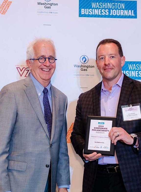 Two men holding a plaque in front of a Washington Business Journal banner. at Northlake Park Apartments, Orlando, Florida
