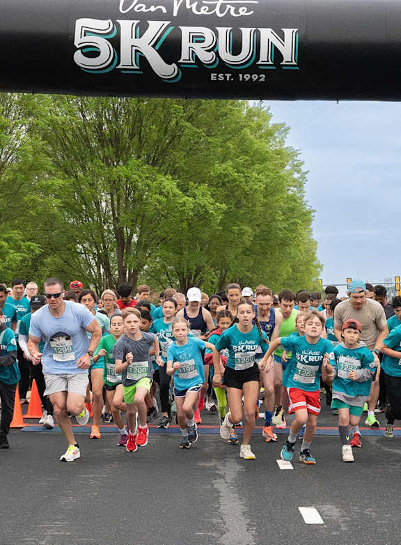 A group of people in blue shirts are running in a Van Meter 5K Run. at Northlake Park Apartments, Florida