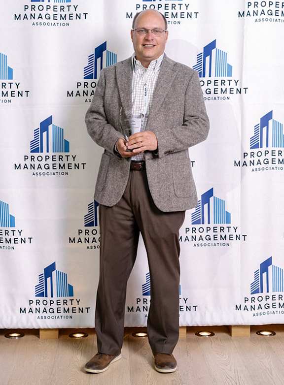 A man in a grey blazer and white shirt stands in front of a backdrop with the words  at Northlake Park Apartments, Florida, 32827