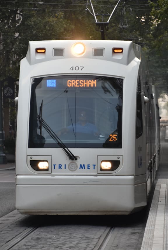 A TriMet train with the number 407 and destination Gresham is stopped at the station.