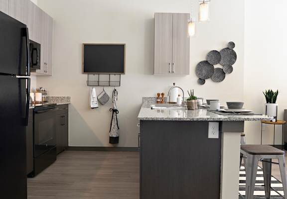 a kitchen with a large island and a black refrigerator  at The Liberty Lofts, Gainesville, TX, 76240