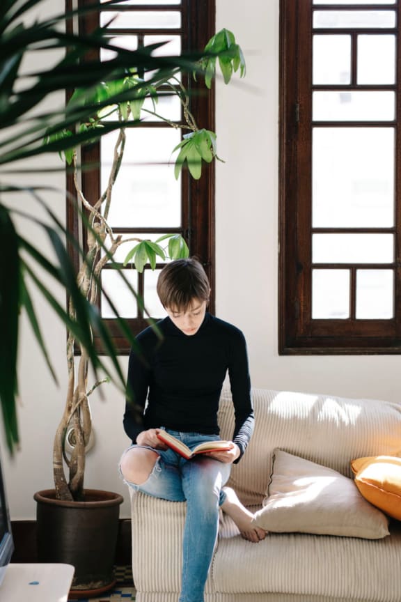a woman sitting on a couch reading a book