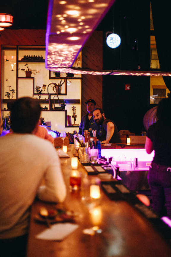 a bar with people sitting at it and standing at the bar