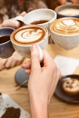 a group of people holding up coffee mugs