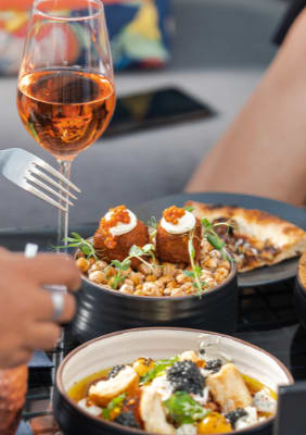 a group of people sitting around a table eating food and drinking wine