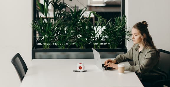a woman sitting at a table with a laptop and coffee