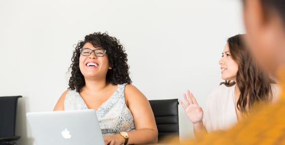 a group of people sitting at a table with a laptop