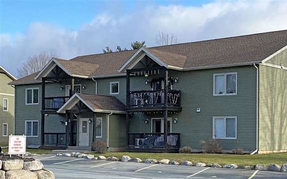 A building with a green siding and a balcony with a railing.