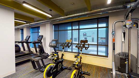 A gym with exercise bikes and a treadmill at The Bessemer at Seward Commons Apartments, Minneapolis, MN,  55404