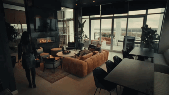 A woman in a black dress walks through a modern living room.