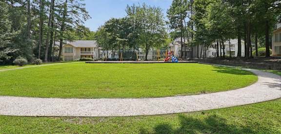A park with a playground and a house in the background.