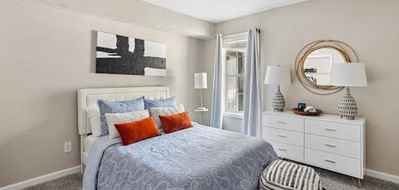 A bedroom with a bed, nightstand, and a mirror.