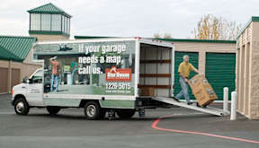 A truck is parked in front of a garage with a sign that says "If your garage needs a map, call us.".