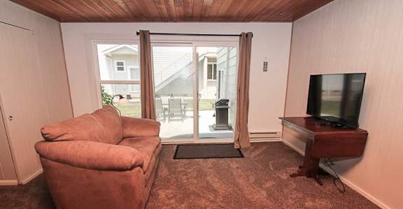 A living room with a chair, a television, and a sliding glass door.