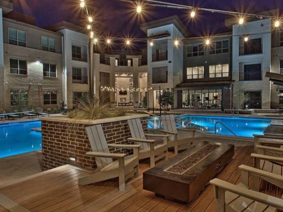 a swimming pool with rocking chairs in front of an apartment building at Hunters Creek Apartments, Texas