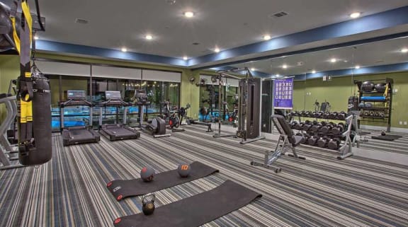a gym with a lot of machines in it at Hunters Creek Apartments, Denton, TX