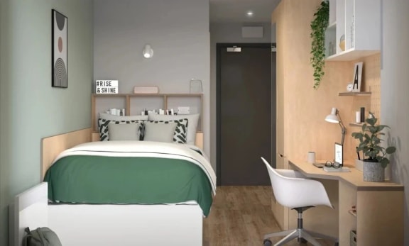 a bedroom with green and white bedding and a wooden desk with a white chair