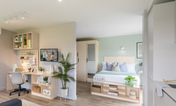 a bedroom with a desk and kitchenette