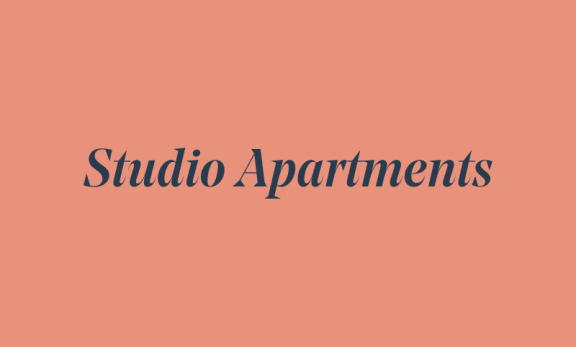 a bedroom with a desk and kitchenette
