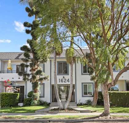A white two-story house with a tree in front.