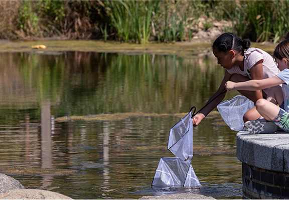 Two children are playing with paper boats in a pond.at Penny Green Apartments, St Neots, WINTRINGHAM