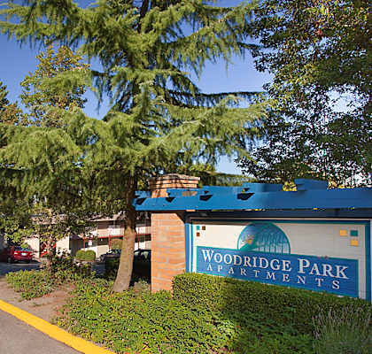 A sign for Woodridge Park Apartments is on the side of a street.