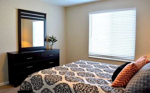 Bedroom with plenty of natural light, queen size bed, dresser and mirror