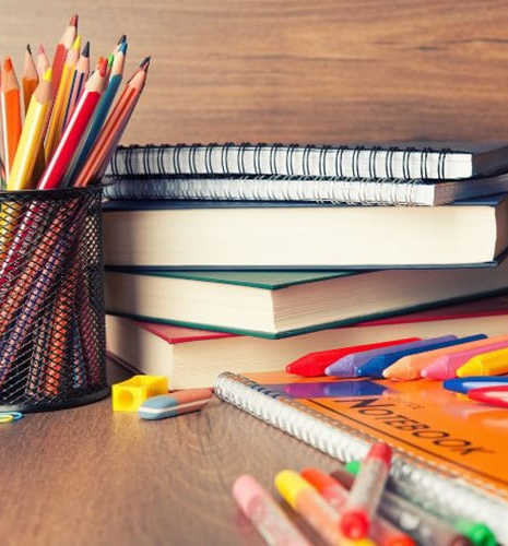 A collection of school supplies including books, notebooks, and colored pencils.