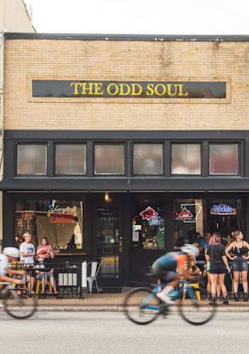 A group of people riding bikes in front of a store called The Odd Soul.
