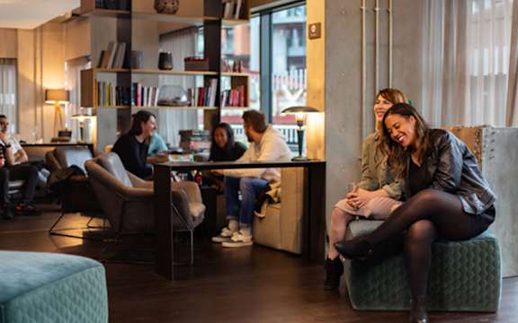 A group of people are sitting and talking in a modern living room.at Slate Yard Apartments, Salford