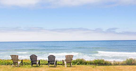 Four chairs are lined up on a beach.