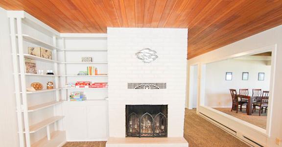 A white fireplace with a wooden mantle and a fire place.