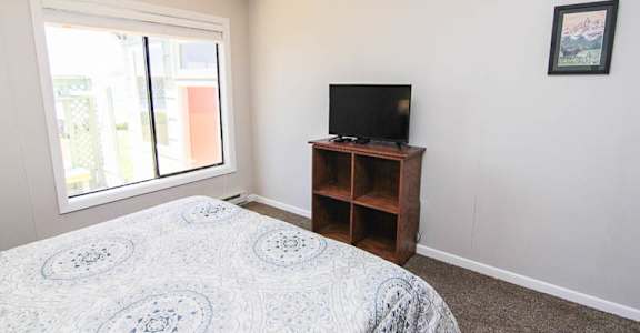 A bedroom with a bed, a television, and a window.