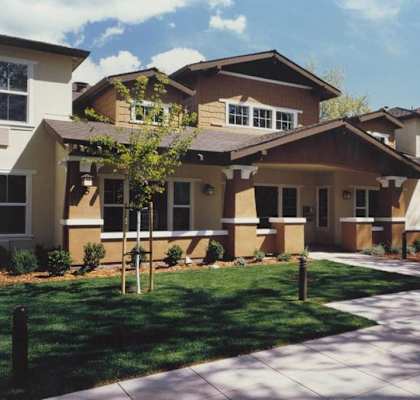 A row of houses with a sidewalk in front.