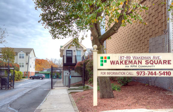 exterior view on building and entrance into the parking lot; sign that reads "Wakeman Square; An RPM Community"