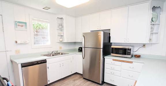 A kitchen with white cabinets and a stainless steel refrigerator.