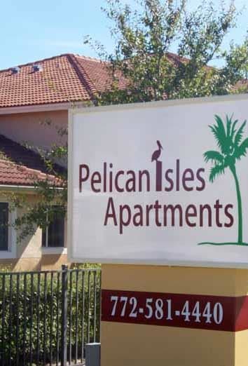 the front of a brick building with a sign and a tree