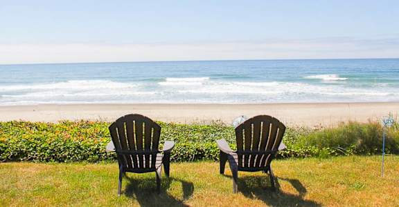 Two chairs are facing a beach.