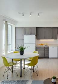 A modern kitchen with a white fridge and yellow chairs.