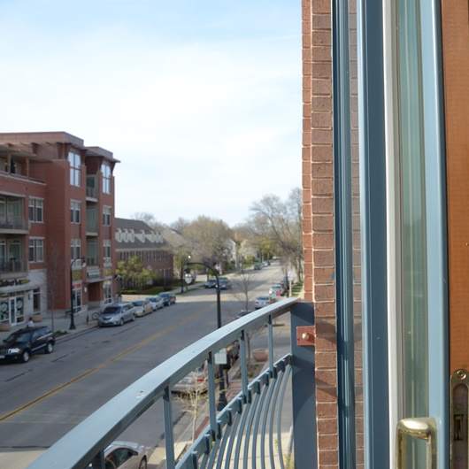 A view of a street from a window with a balcony. at Cornerstone & Ravenna* Apartments, Shorewood, Wisconsin