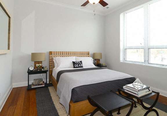 a bedroom with a bed and a chair and a window